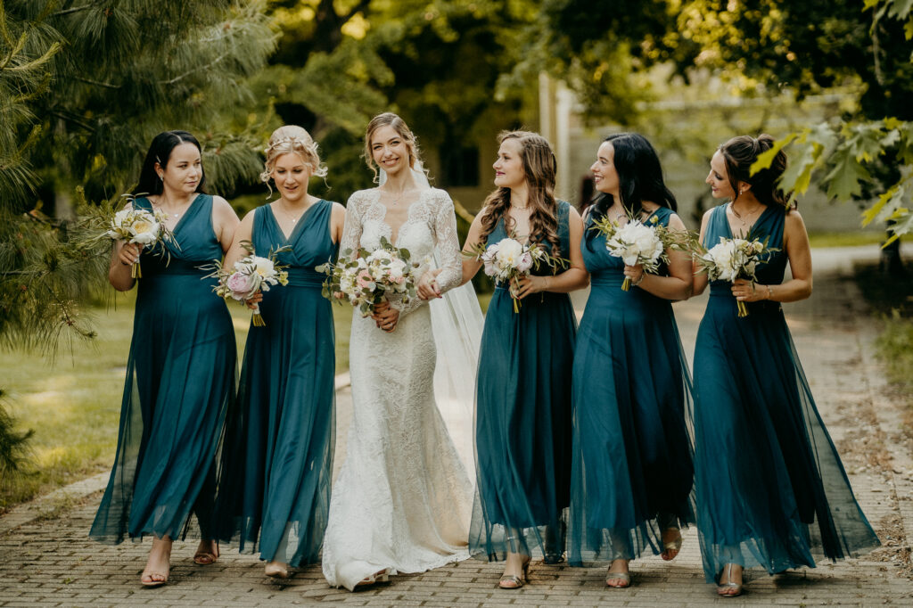 Menyasszony koszorúslányokkal sétál a Fenyőharaszti Kastélyszálló parkjában, esküvői fotózás